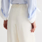 Person shown from the back wearing TWP's Hudson St Pant in white, paired with a light blue, long-sleeved shirt, hands resting by their sides.