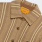 Close-up of the Dylan Stripe Shirt by Guest in Residence, a brown and beige striped button-down with herringbone pattern and yellow brand label on the collar. Layer over a soft cashmere sweater for extra warmth and style.