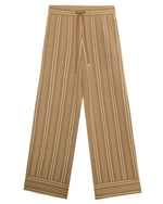 The Stripe Lounge Pant by Guest in Residence features brown and beige vertical stripes, a drawstring waist, and decorative hem stripes—offering stylish comfort as women’s loungewear.