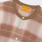 A close-up of the Guest in Residence Shadow Plaid Cardigan, a fuzzy cashmere blend in beige, white, and pink stripes with white buttons and a visible inside collar label.