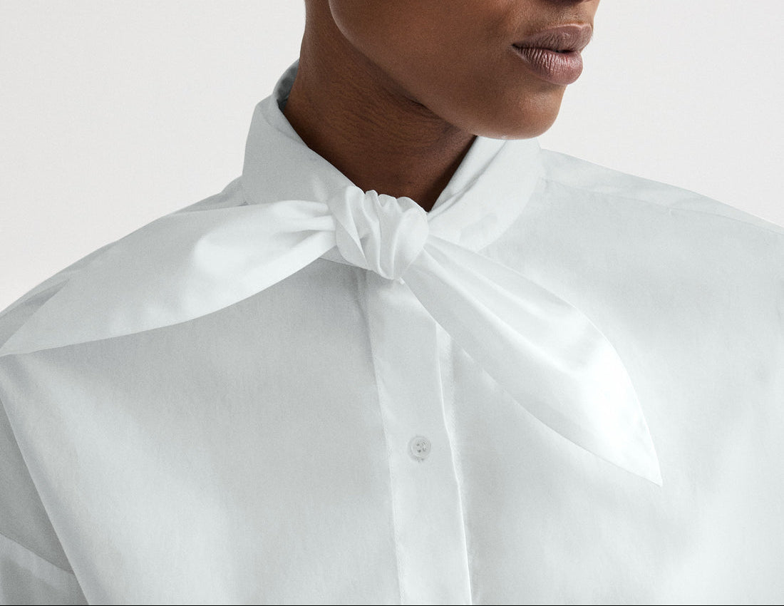A person wearing the TWP Tie One On Shirt, styled with a white scarf knotted at the neck.