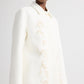 A model wears the TWP Edinburgh Coat, a knee-length car coat featuring a collar and subtle light floral embroidery on the front, photographed from the shoulders down against a plain background.