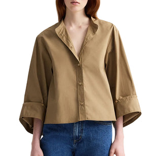 A person wears the TWP Beau Shirt, featuring a relaxed silhouette and wide sleeves, paired with blue jeans while standing against a white background.