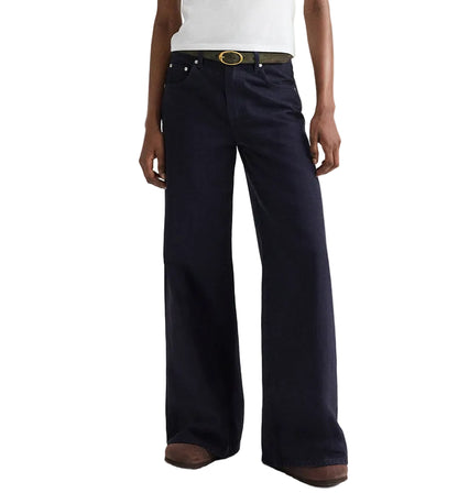 A person wearing the TWP Tiny Dancer Pant—a relaxed fit, wide leg jean—styled with a black belt and brown shoes stands against a white background.