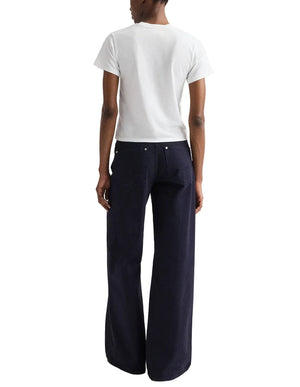 A person stands with their back to the camera, wearing a white short-sleeve t-shirt and TWP Tiny Dancer Pant—high-waisted, wide-leg jeans in a relaxed fit for a vintage-inspired denim look.