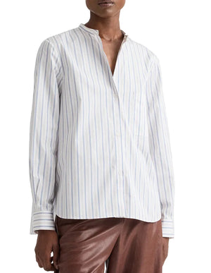 A person wears the Tied Down Stripe Shirt by TWP—white with vertical light blue and beige stripes—and brown pants, standing against a plain background.