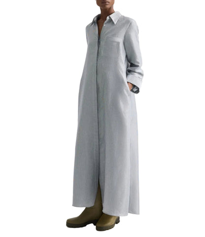 A person wearing the TWP Jenny's Glossy Mini Stripe Gown, an oversized light gray shirtdress with a collar and long sleeves, paired with olive green boots.