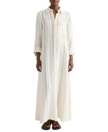 A person wearing TWP's Jenny's Ladder Weave Linen Gown, an oversized maxi shirtdress with a relaxed silhouette and vertical perforated stripes, paired with black sandals.