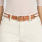 Person wearing high-waisted white jeans with Frame's The Riviera Belt, a slim cow leather belt with a polished buckle, over a fitted light beige ribbed top.