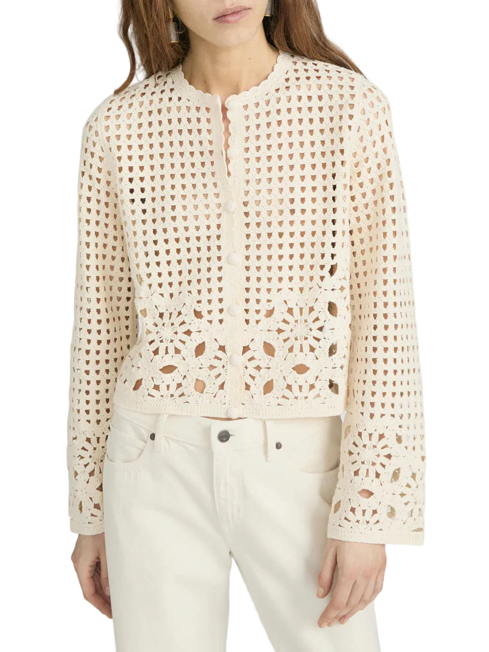 A woman wearing The Postcard Cardi by Frame, an off-white long-sleeve crochet cardigan with a scalloped neckline, paired with matching off-white pants.