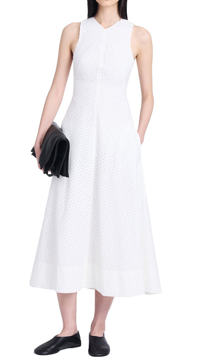 Person wearing a sleeveless white Proenza Schouler Juno Dress with an embroidered overlay, holding a black clutch purse, and black shoes.