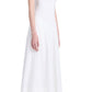 A person standing in profile, wearing a sleeveless white Proenza Schouler Juno Dress with Broderie Anglaise details and black flat shoes against a white background.