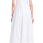 A person is wearing a sleeveless white Proenza Schouler Juno Dress with a keyhole back and a tie closure. The dress, adorned with an embroidered overlay, has a textured pattern and reaches mid-calf. They are also wearing black shoes.