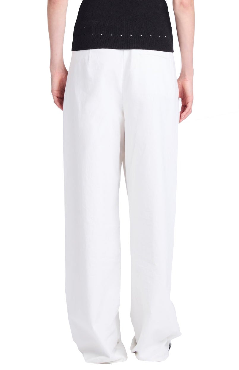 A person is seen from the back wearing the Proenza Schouler Helena Pant, showcasing relaxed white wide-leg trousers paired with a black top.