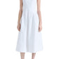 A person is standing wearing a sleeveless, white, mid-length Proenza Schouler Shelby Dress with a fit and flare silhouette and white slip-on shoes, against a plain white background.