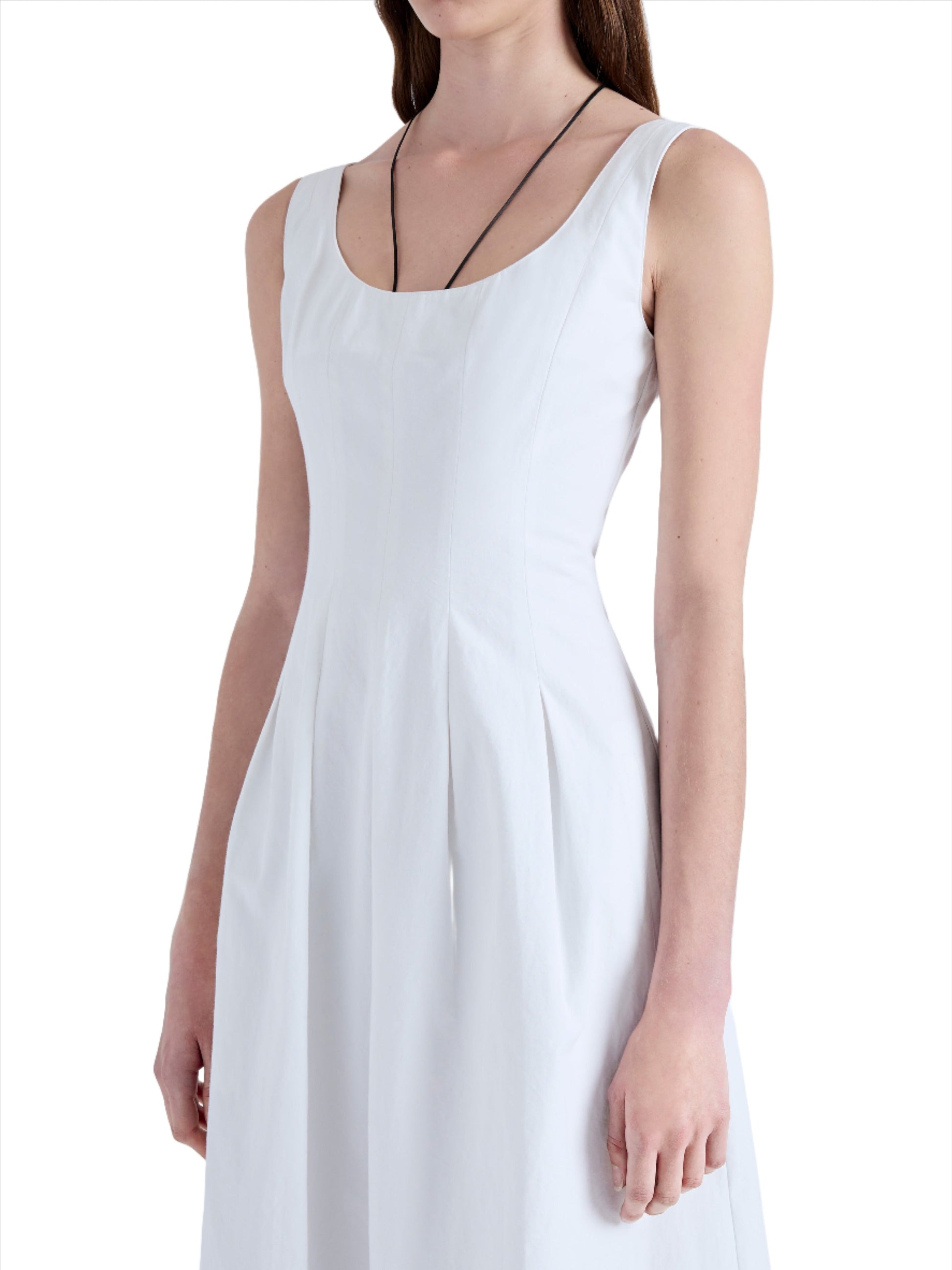 Woman wearing a sleeveless, scoop-neck white Proenza Schouler Shelby Dress made of Cotton Linen, standing against a white background with her head cropped out of the frame.