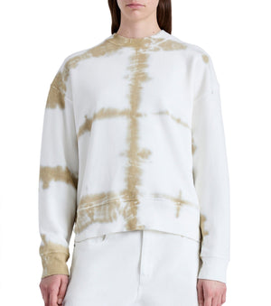 Wearing the Proenza Schouler Blake Tie Dye Sweatshirt by Proenza Schouler White Label, a person presents a laid-back silhouette with its white and tan tie-dye pattern, complemented by crisp white pants against a plain background.