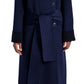 Dressed in the Proenza Schouler White Label Constance Pinstripe Melton Coat, featuring a wide collar, large buttons, a double-breasted silhouette, black cuffs, and a self-tie belt, paired with blue jeans and black shoes.