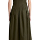 A person is seen from the back wearing a Proenza Schouler Marley Dress, a sleeveless, knee-length piece in olive green with buttons and tie details at the bottom, featuring an adjustable bubble hem. Paired with black shoes, the dress showcases its unique tech cotton fabric.