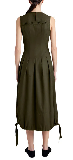 A person is seen from the back wearing a Proenza Schouler Marley Dress, a sleeveless, knee-length piece in olive green with buttons and tie details at the bottom, featuring an adjustable bubble hem. Paired with black shoes, the dress showcases its unique tech cotton fabric.