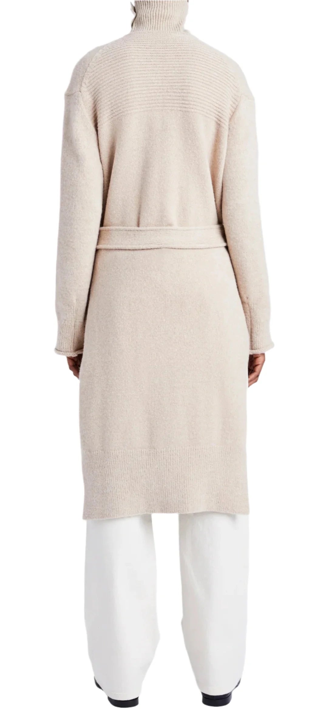 A person is seen from the back, wrapped in a cozy Proenza Schouler Lenora Wool Cardigan with a self-tie belt elegantly secured over crisp white pants.