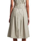 The Proenza Schouler White Label Caro Dress Brushed Poplin is knee-length, sleeveless, and beige with a V-back and A-line silhouette. Its pleated skirt pairs elegantly with black sandals, making it stand out against the plain background.