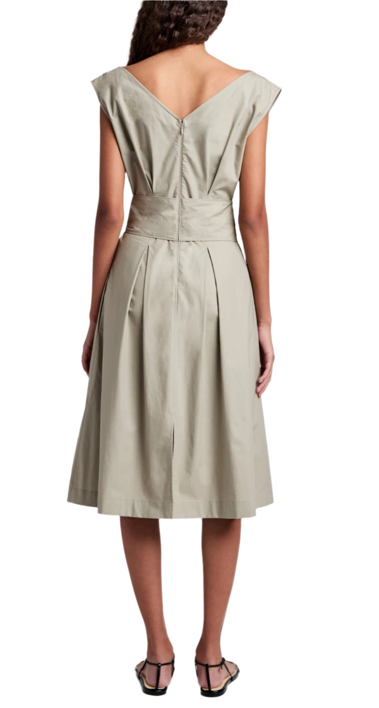 The Proenza Schouler White Label Caro Dress Brushed Poplin is knee-length, sleeveless, and beige with a V-back and A-line silhouette. Its pleated skirt pairs elegantly with black sandals, making it stand out against the plain background.
