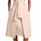 A person is dressed in a beige, sleeveless Proenza Schouler White Label Caro Dress in brushed poplin, featuring an A-line silhouette and self-tie waist belt, paired with black sandals.