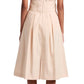 The Proenza Schouler White Label Caro Dress Brushed Poplin showcases an A-line silhouette with a self-tie waist belt, beige knee-length design, cap sleeves, and a pleated skirt. The woman in the dress stands with her back to the camera, highlighting black sandals.