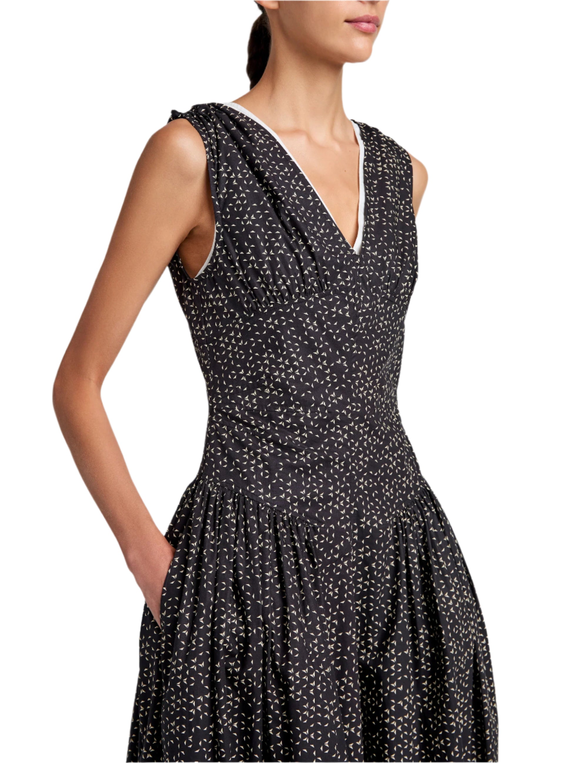 Someone is wearing a sleeveless Proenza Schouler White Label Clayton Dress Printed Poplin in black with white dots. The dress includes a V-neckline and a flared skirt, enhancing its elegance.