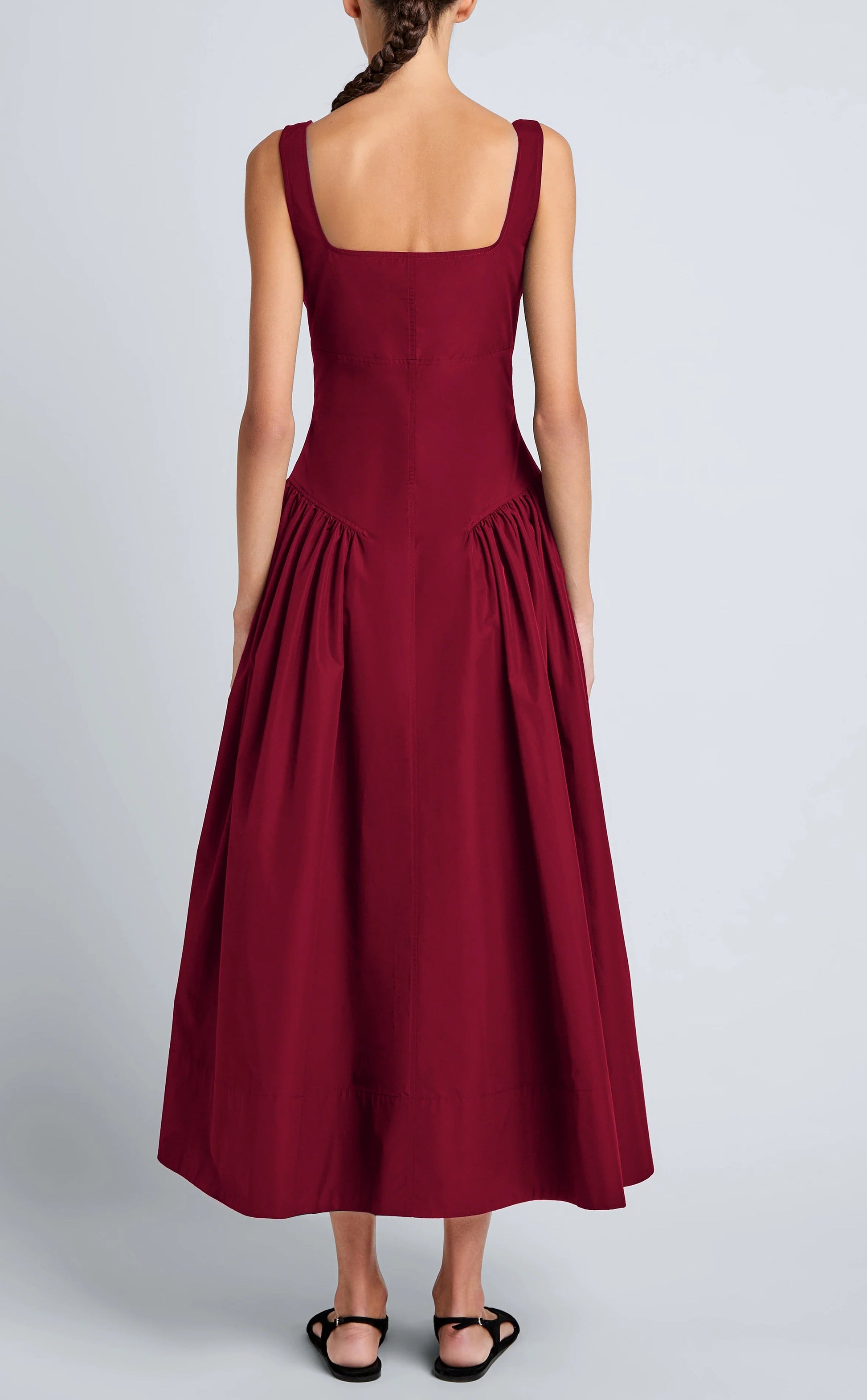 A woman models the Kendall Dress by Proenza Schouler White Label—a sleeveless, ankle-length burgundy dress with a square neckline—elegantly shown from the back against a plain light background. Made from soft Tech Cotton.