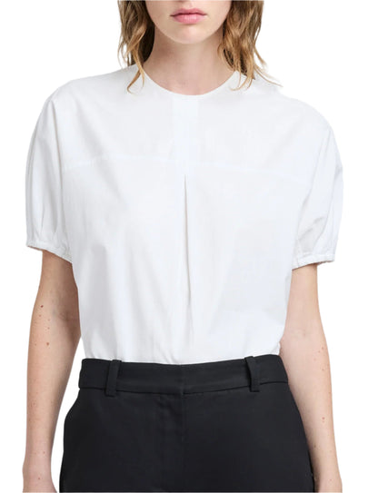 Against a plain background, the person wears the Proenza Schouler White Label Haleigh Top in cotton sateen. Its white short sleeves are tucked into black pants, effortlessly combining elegance with simplicity.