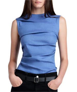 A person models the Proenza Schouler White Label Anoushka Top Linen Slub, a sleeveless blue top, paired with black pants, hands casually tucked in pockets against a plain white background.