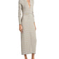 A person wearing the Proenza Schouler White Label Ivanna Dress Micro Check, a long button-up knit with a beige and white pattern and chic V-neckline, paired with black strappy sandals.