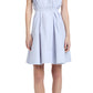 A woman wears the Kenzie Dress Linen by Proenza Schouler White Label, a sleeveless, light blue, knee-length fit-and-flare in Linen Shirting with buttons, waist tie, and black strappy sandals.