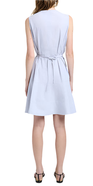 A woman with her back to the camera wears a sleeveless light blue Kenzie Dress Linen by Proenza Schouler White Label, featuring a waist tie and black sandals, highlighting its elegant fit-and-flare silhouette.