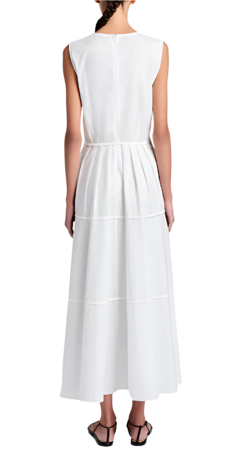 A person seen from the back wears the Kailey Dress Stretch Poplin by Proenza Schouler White Label—a sleeveless, white, ankle-length pleated dress with a V-neckline—paired with black sandals.