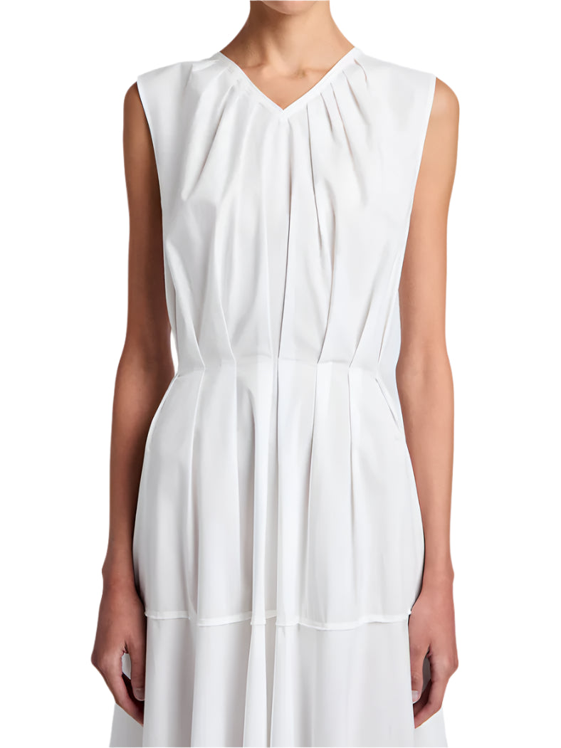 A person wears the Proenza Schouler White Label Kailey Dress Stretch Poplin, a sleeveless white pleated dress with a V-neckline, shown from shoulders to mid-thigh.