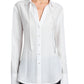A woman wears the Proenza Schouler White Label Cami Shirt Crinkle Viscose in white, a relaxed-fit top with a collar, long sleeves, and subtle trim at the hem, paired with black pants.