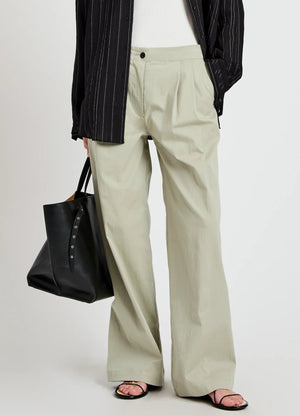 A person wears the Proenza Schouler White Label Romina Pant—relaxed fit, light beige, wide-leg—paired with a white top, black pinstripe shirt, black tote bag, and black sandals.