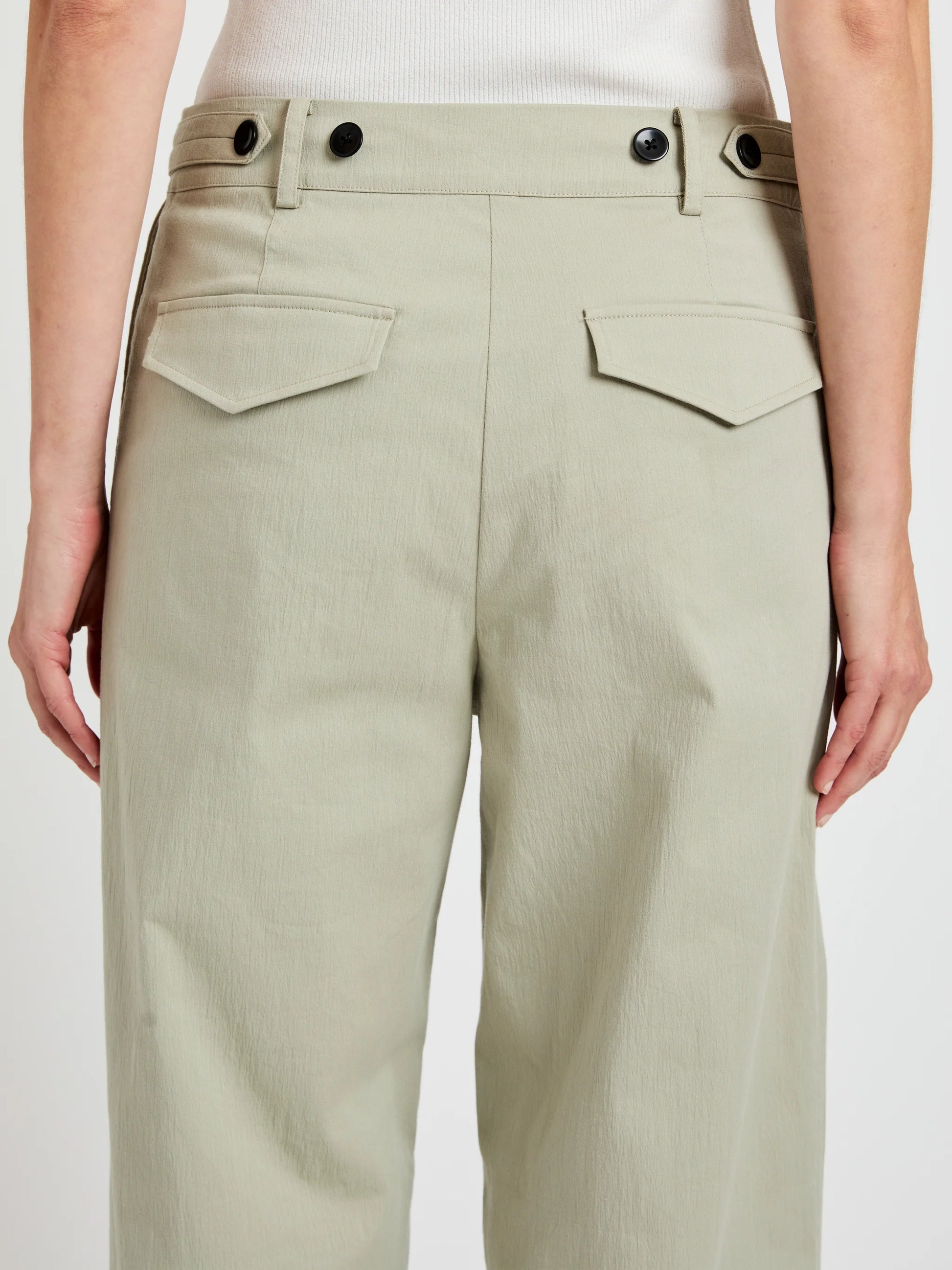 A person shown from behind, waist down, wears the Proenza Schouler White Label Romina Pant—relaxed fit, light khaki cotton with flap back pockets and black buttons.