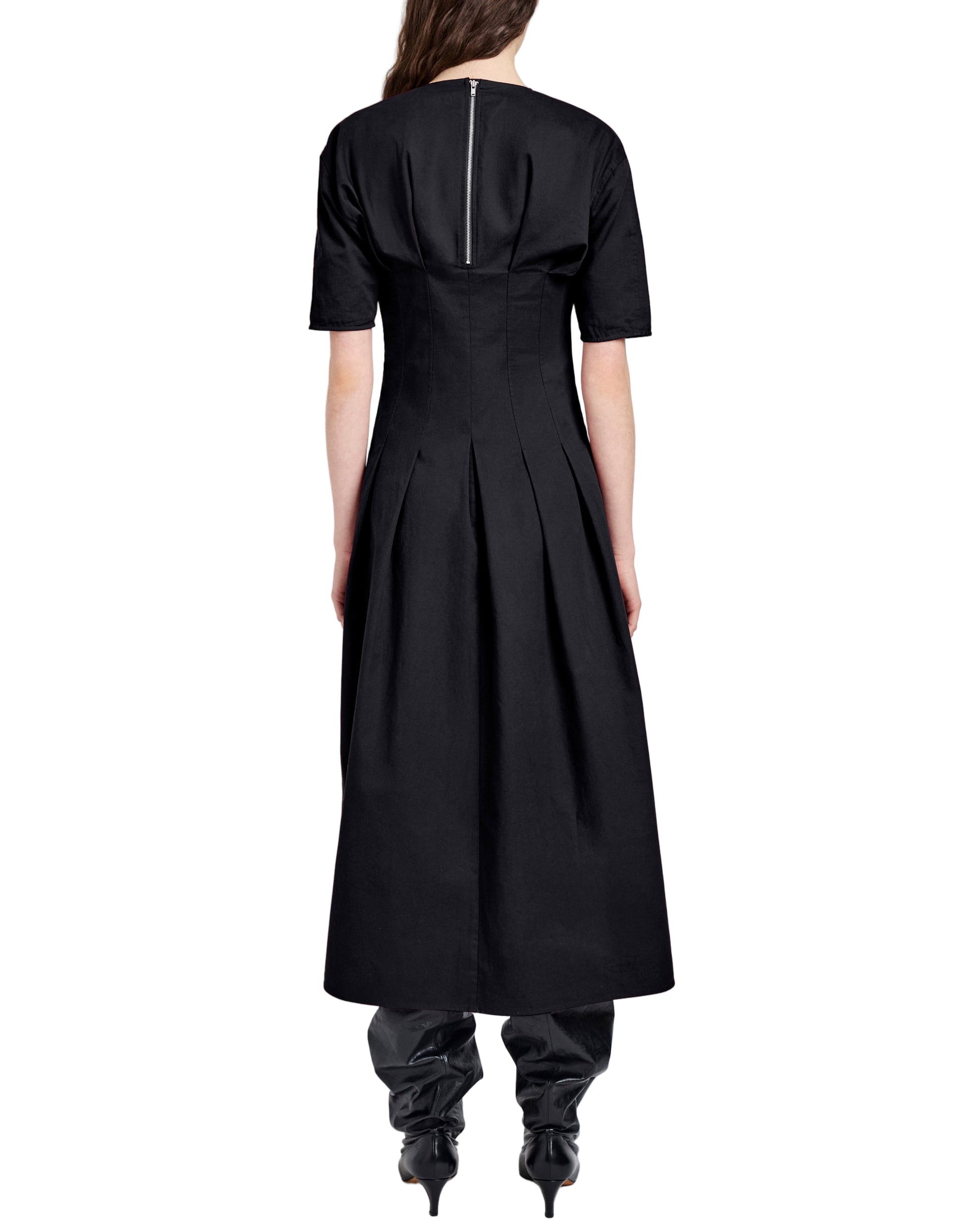 A person viewed from behind wears the Proenza Schouler White Label Ainsley Dress in black Tech Cotton, featuring an A-line silhouette, short sleeves, pleats, ankle length, and a back zipper, paired with black pointed-toe boots.