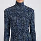 A person wearing a long-sleeve Mabel Cheetah Jersey Dress by Proenza Schouler White Label, featuring a blue and white abstract pattern on a black background.