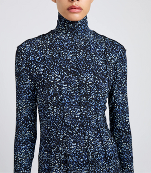A person wearing a long-sleeve Mabel Cheetah Jersey Dress by Proenza Schouler White Label, featuring a blue and white abstract pattern on a black background.