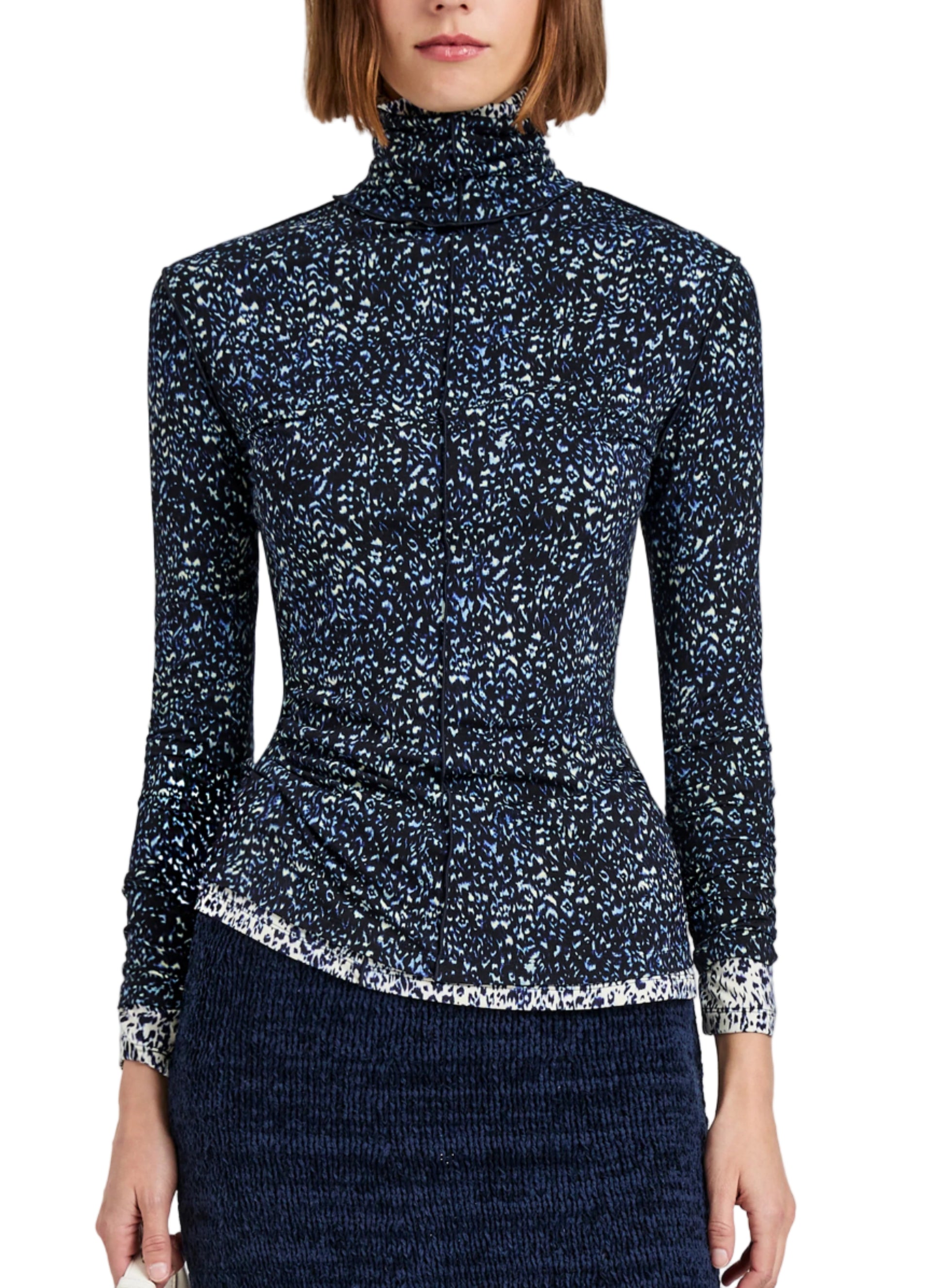 A woman wears the Proenza Schouler White Label Audrey Cheetah Jersey Top, a long-sleeve, turtleneck style with a subtle blue and white pattern, paired with a textured dark skirt. The image is cropped at the shoulders and thighs.