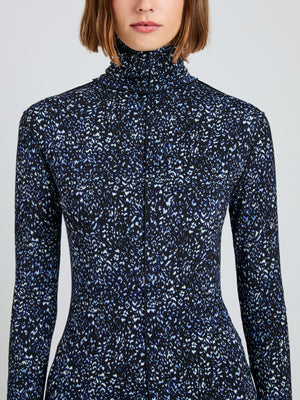 A woman wears the Audrey Cheetah Jersey Top by Proenza Schouler White Label, a long-sleeve, high-neck fitted turtleneck with a blue and white abstract print on black.