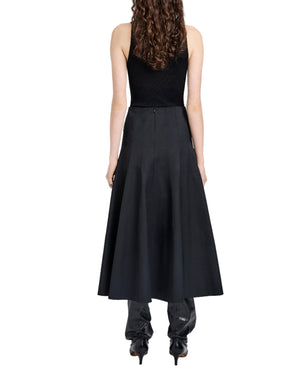 A person with long curly hair, in a sleeveless black top, the Proenza Schouler White Label Heidi Skirt with an A-line silhouette, and black heeled boots, stands with their back to the camera.