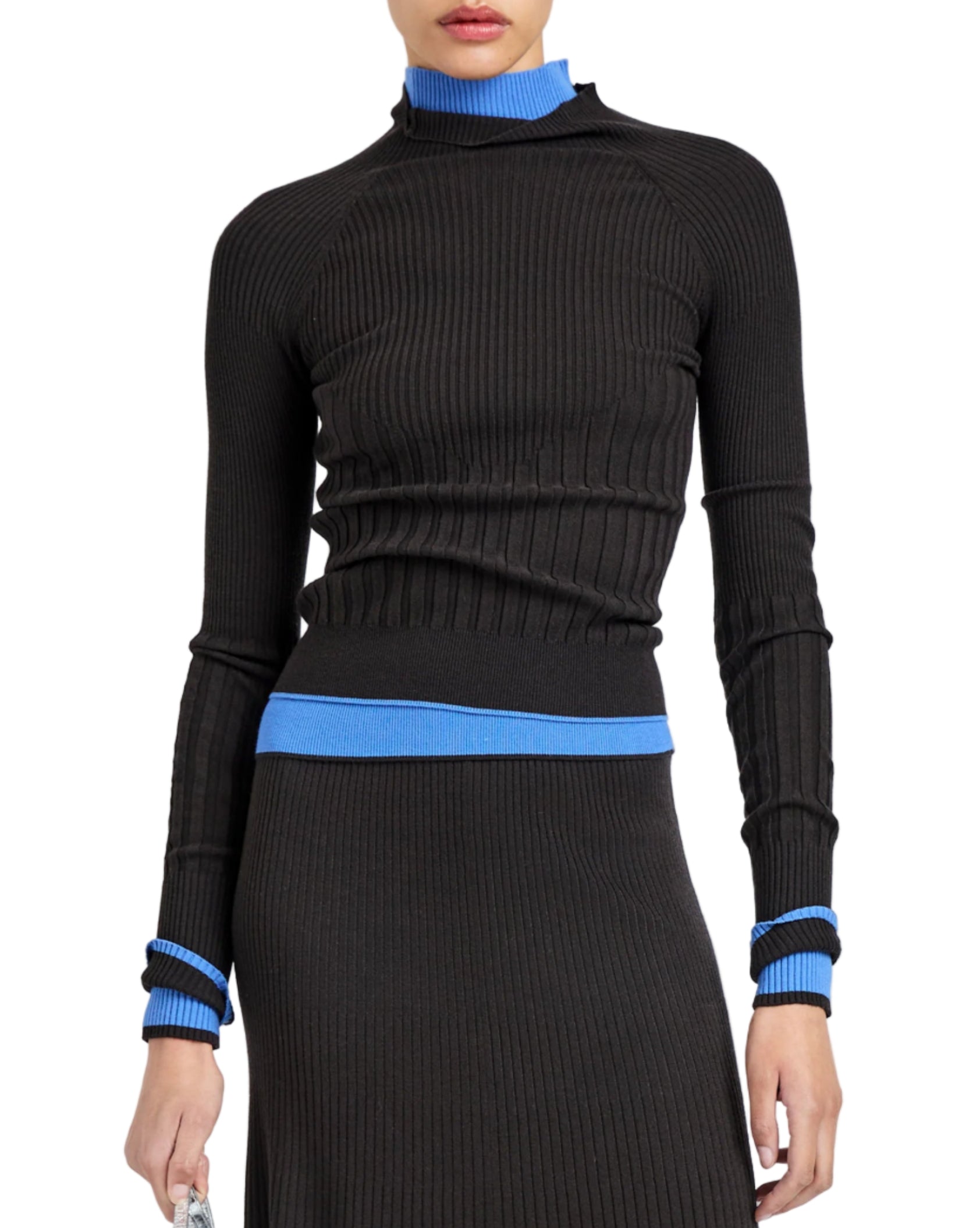 A person wears the Proenza Schouler White Label Daniella Sweater—a ribbed black turtleneck with blue collar, waist, and cuff accents—paired with a matching black skirt.