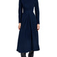 A woman wears the Sai Wool Jersey Dress by Proenza Schouler White Label—a navy, long-sleeved, ankle-length dress with pleats and an A-line silhouette—paired with black heeled boots.