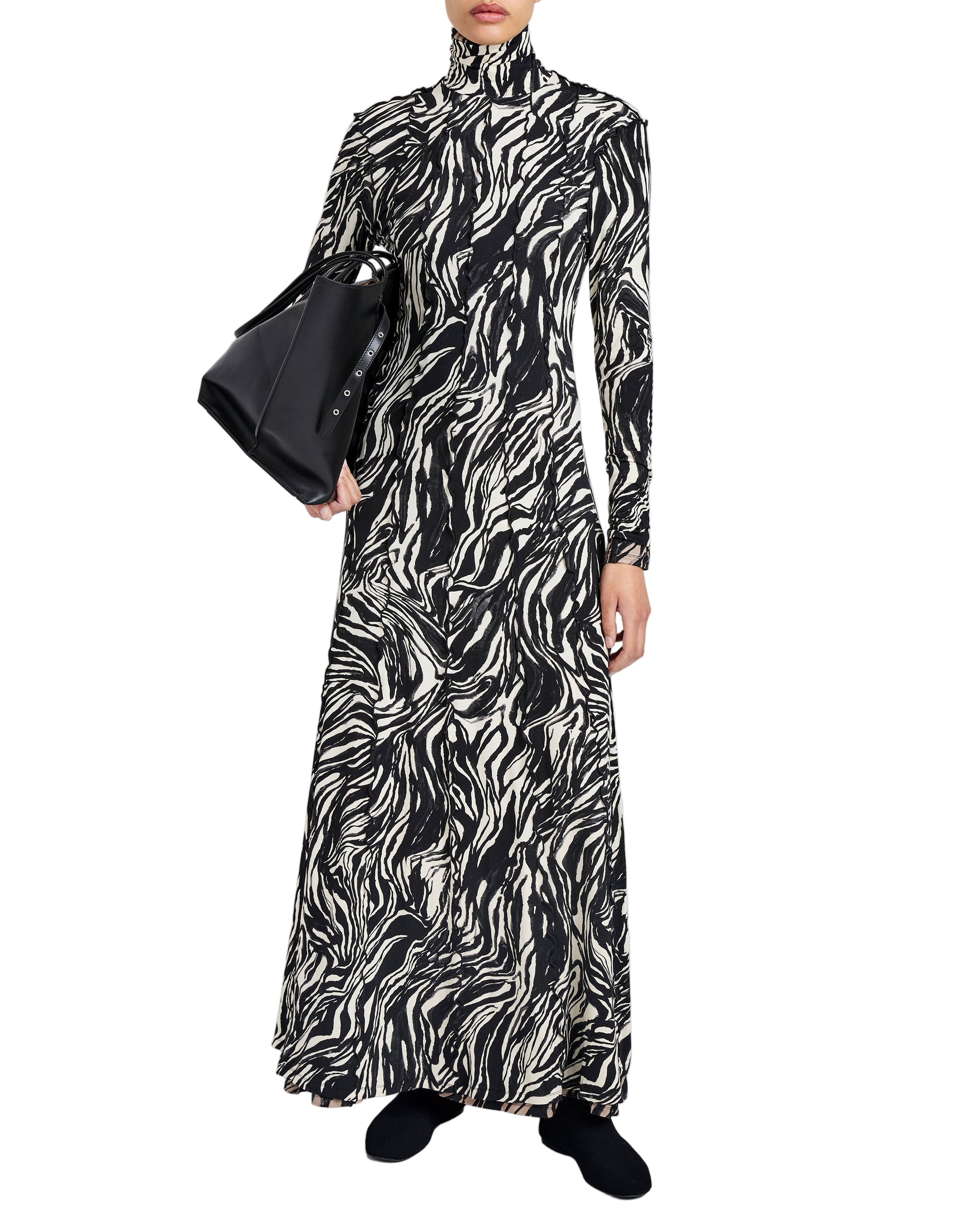 Wearing the Proenza Schouler White Label Mabel Marble Jersey Dress, this person pairs the black and white long-sleeve look with a black handbag and matching shoes.